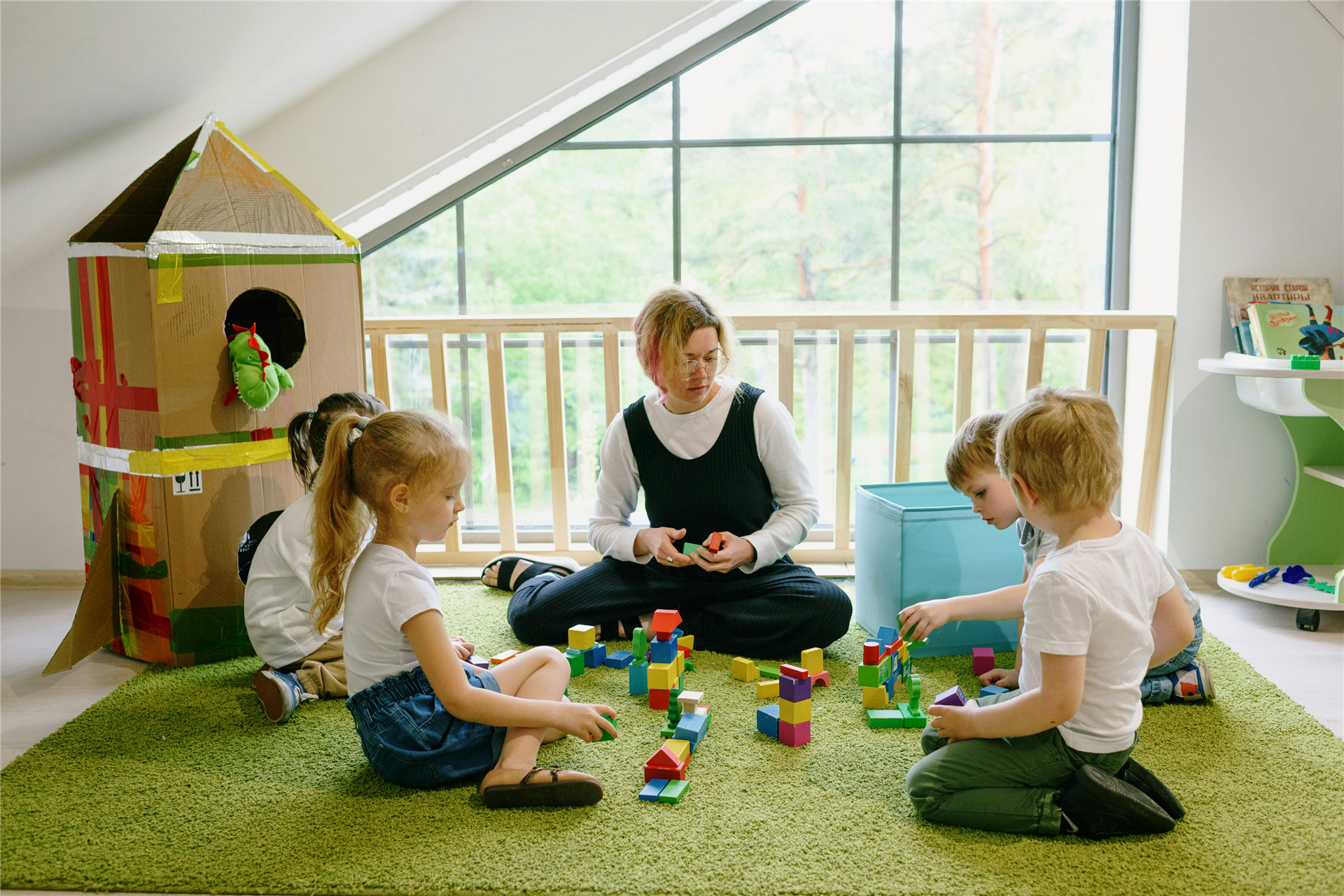 Person playing blocks on the floor with children